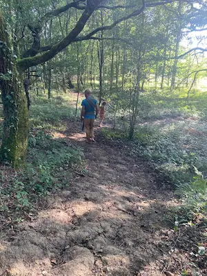 Famille marchant pieds nus sur un chemin de terre en forêt sur le sentier pieds nus du Domaine de Larrous – Domaine de Larrous, Gaujacq (Landes)