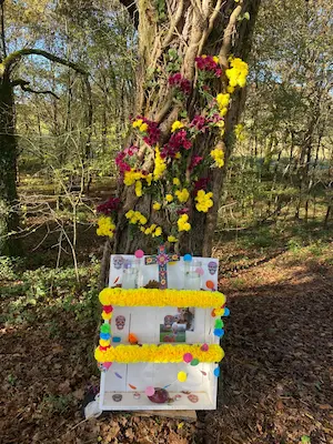 Autel fleuri du Día de los Muertos avec guirlandes et fleurs jaunes et violettes en forêt au Sentier Pieds Nus – Domaine de Larrous, Gaujacq (Landes)