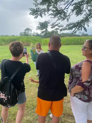 Famille prenant une photo avec la mascotte Mr Pop au Labyrinthe de Chalosse dans les Landes – Domaine de Larrous, Gaujacq (Landes)